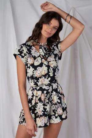 Black Multi Color Floral Print V-Neck Mini Sleeve Tight Fitted Waist Pleated Bottom Romper With Bow Tie Detail