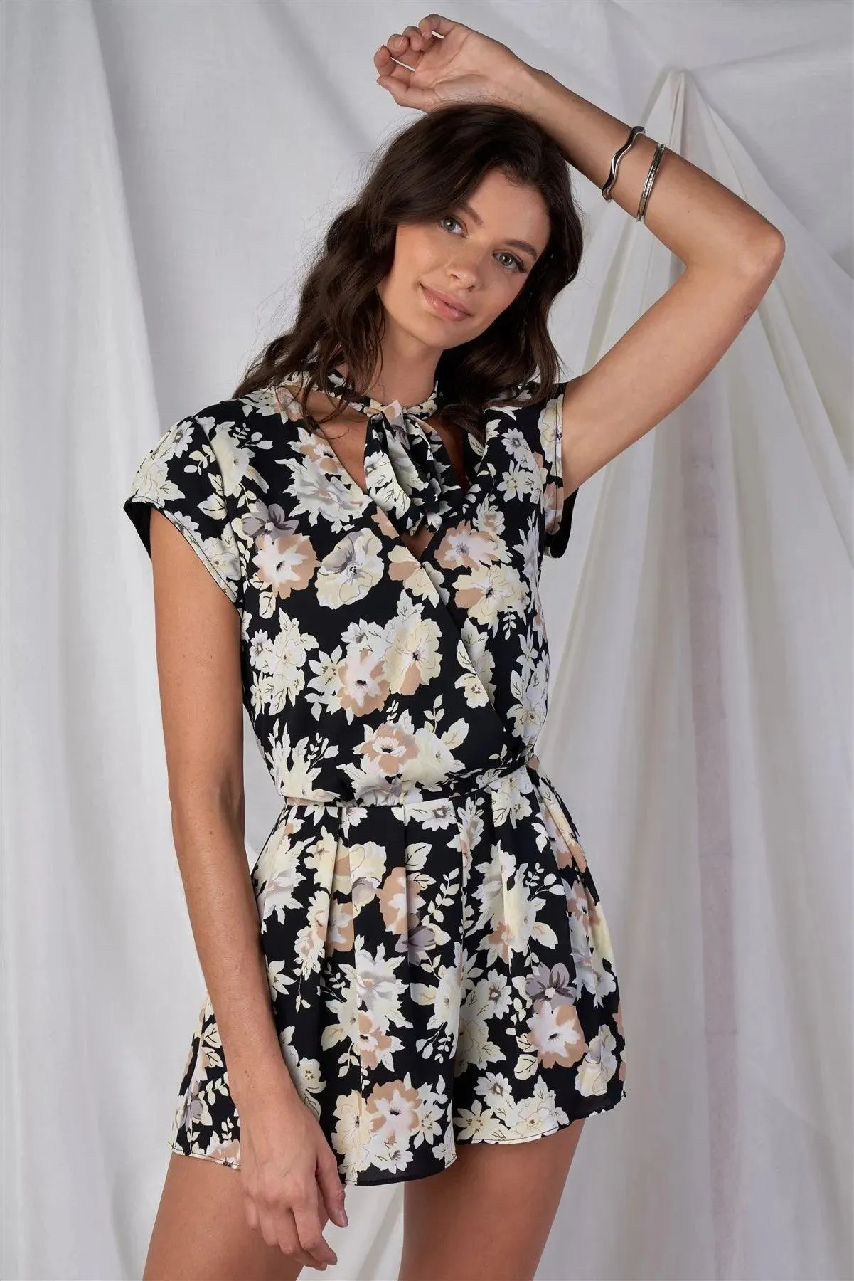 Black Multi Color Floral Print V-Neck Mini Sleeve Tight Fitted Waist Pleated Bottom Romper With Bow Tie Detail