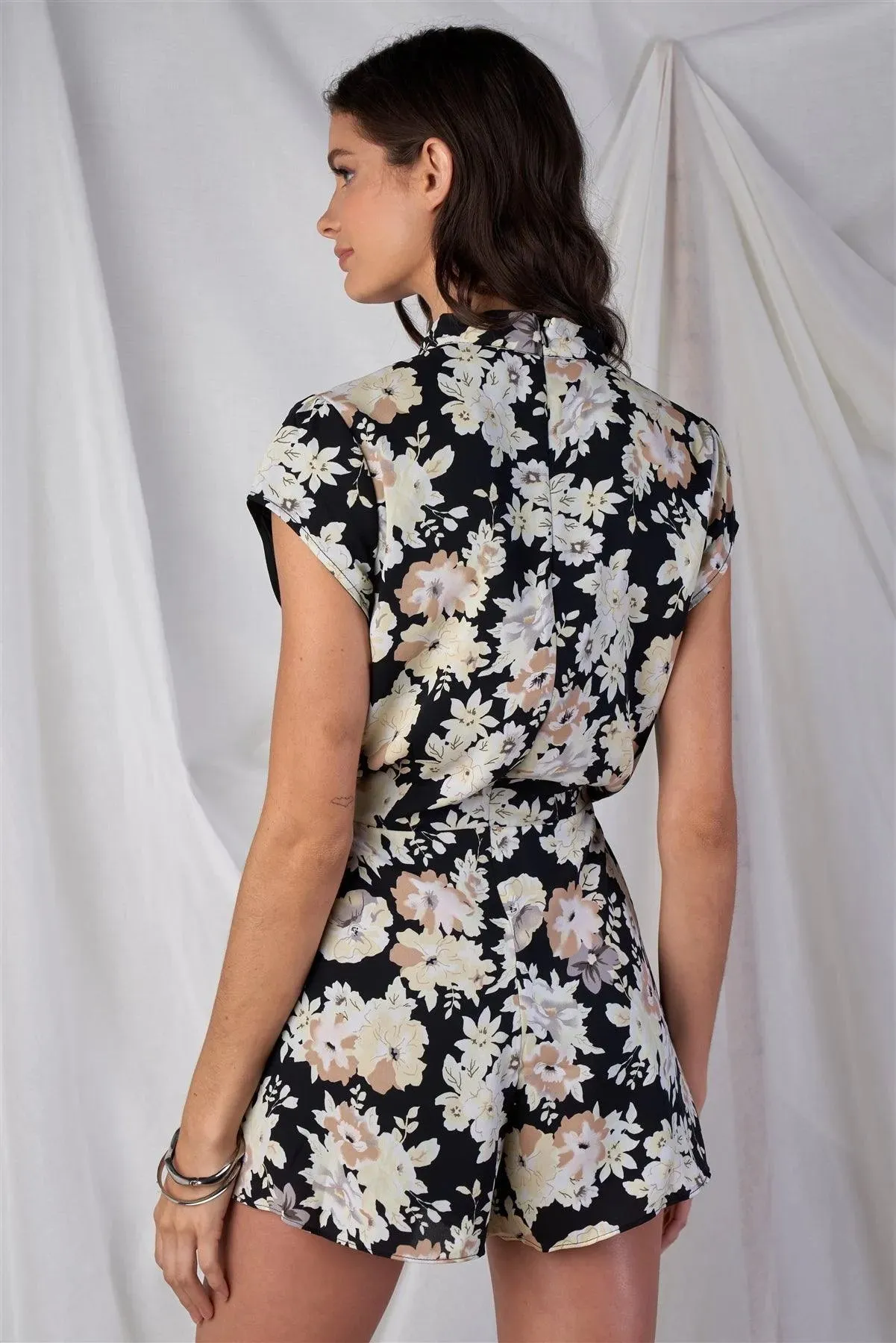 Black Multi Color Floral Print V-Neck Mini Sleeve Tight Fitted Waist Pleated Bottom Romper With Bow Tie Detail